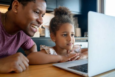 Bir baba kızına ev okulunda yardım ediyor..