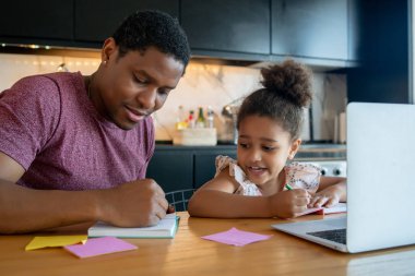 Bir baba kızına ev okulunda yardım ediyor..