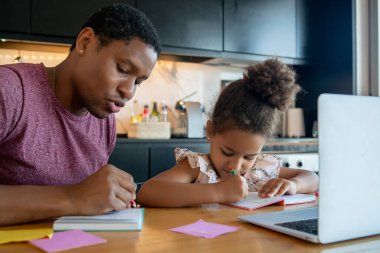 Bir baba kızına ev okulunda yardım ediyor..