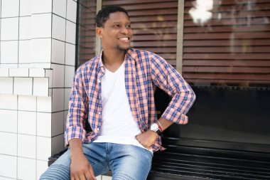 Afro-Amerikalı bir adam mağazanın vitrininde oturuyor..