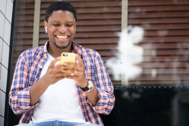 Sokakta telefonunu kullanan Afrikalı Amerikalı bir adam..