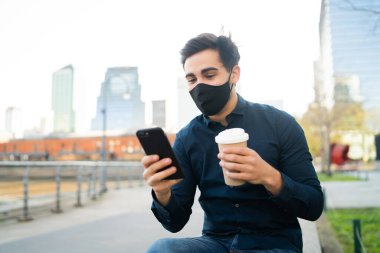 Genç adam cep telefonunu açık havada kullanıyor..