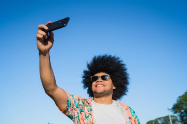 Latin adam dışarıda telefonla selfie çekiyor..