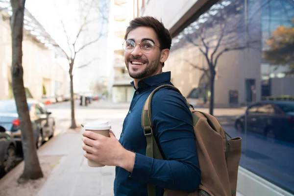 Jongeman met een kopje koffie terwijl hij buiten loopt. — Stockfoto