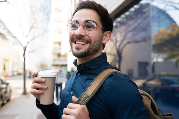 Νεαρός κρατώντας ένα φλιτζάνι καφέ, ενώ περπατάτε έξω. — Φωτογραφία Αρχείου