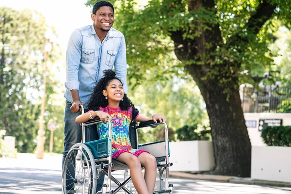 Kleines Mädchen im Rollstuhl genießt Spaziergang mit ihrem Vater. — Stockfoto