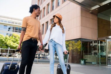 Dışarıda yürürken bavul taşıyan turist çift..