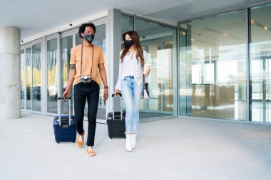 Dışarıda yürürken bavul taşıyan turist çift..