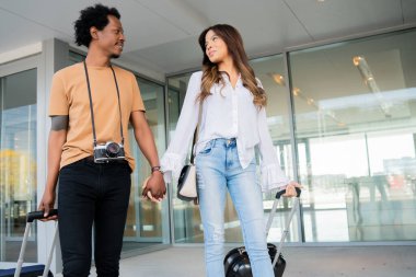 Dışarıda yürürken bavul taşıyan turist çift..
