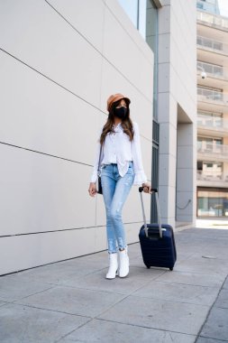 Dışarıda bavul taşıyan genç bir kadın..