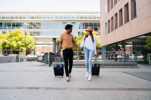 Casal de turistas carregando mala enquanto caminhava ao ar livre. — Fotografia de Stock