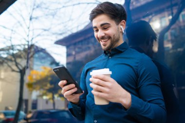 Genç adam cep telefonunu açık havada kullanıyor..