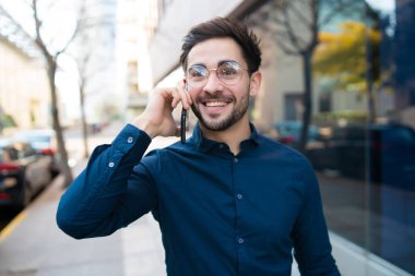 Genç adam dışarıda telefonla konuşuyor..