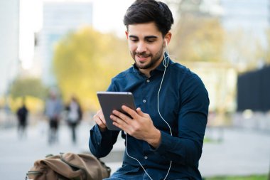 Genç adam dışarıda dijital tabletle video görüşmesi yapıyor..