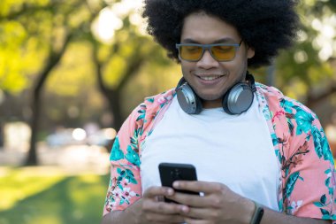 Genç adam cep telefonunu açık havada kullanıyor..