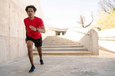 Atletik adam koşuyor ve dışarıda egzersiz yapıyor..