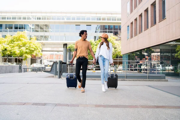 Casal de turistas carregando mala enquanto caminhava ao ar livre. — Fotografia de Stock