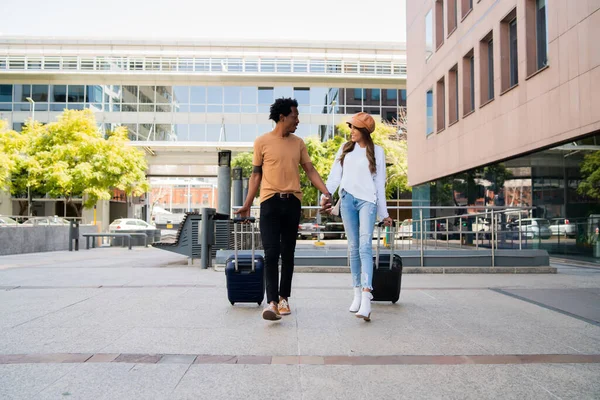 Casal de turistas carregando mala enquanto caminhava ao ar livre. — Fotografia de Stock