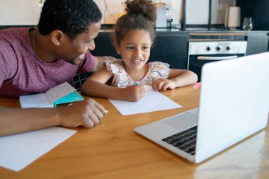 Bir baba kızına ev okulunda yardım ediyor..