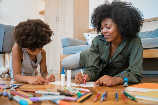 Moeder en zoon tekening met gekleurde potloden op de vloer. — Stockfoto