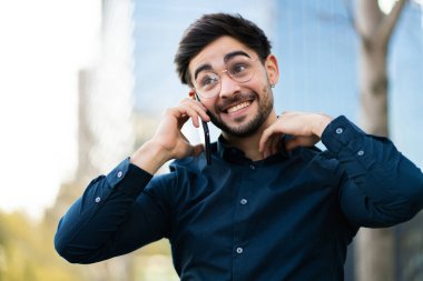 Genç adam dışarıda telefonla konuşuyor..