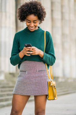 İş kadını cep telefonunu açık havada kullanıyor..