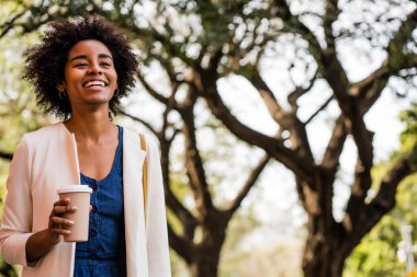 Afro iş kadını elinde bir fincan kahve tutuyor..