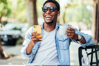 Kafede cep telefonuyla görüntülü görüşme yapan bir adam..