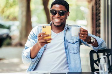 Kafede cep telefonuyla görüntülü görüşme yapan bir adam..