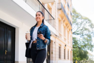 Cep telefonunu kullanan genç bir kadın..