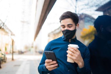 Genç adam cep telefonunu açık havada kullanıyor..