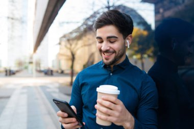 Genç adam cep telefonunu açık havada kullanıyor..