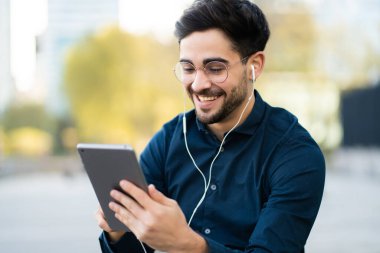 Genç adam dışarıda dijital tablet kullanıyor..