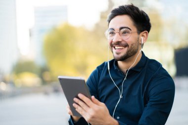 Genç adam dışarıda dijital tabletle video görüşmesi yapıyor..