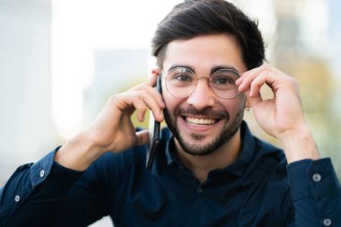 Genç adam dışarıda telefonla konuşuyor..