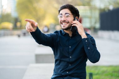 Genç adam dışarıda telefonla konuşuyor..