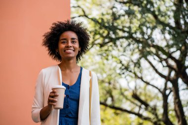Afro iş kadını elinde bir fincan kahve tutuyor..