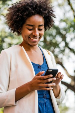 İş kadını cep telefonunu açık havada kullanıyor..