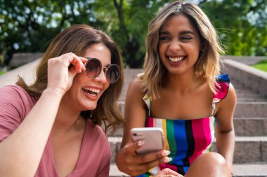 Dışarıda cep telefonu kullanan iki arkadaş..