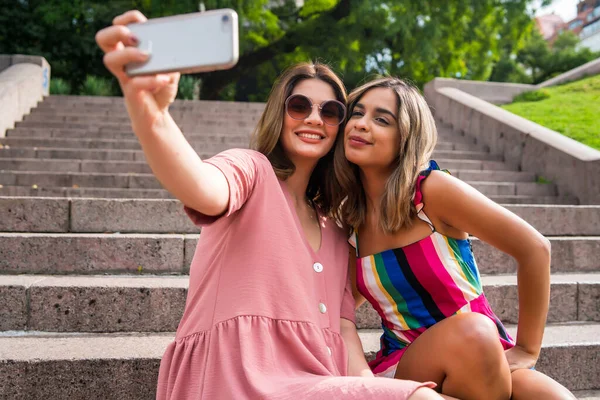 İki arkadaş dışarıda telefonla selfie çekiyor..