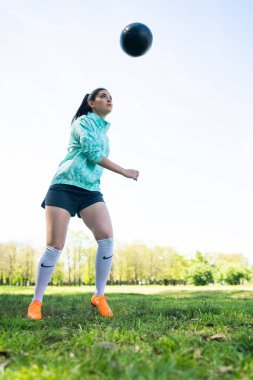 Genç bir kadın topla futbol oynuyor..