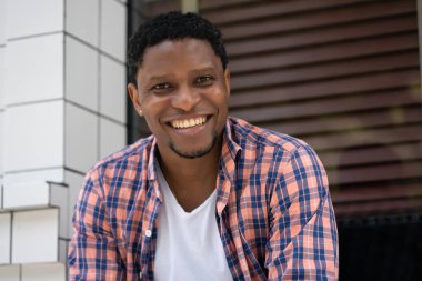 Afro-Amerikalı bir adam mağazanın vitrininde oturuyor..