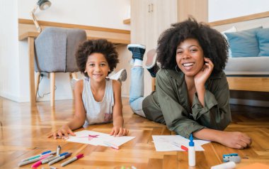 Anne ve oğul yere renkli kalemler çiziyor..