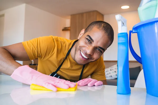 Young latin man cleaning at home.