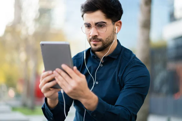 Young man having a video call on digital tablet outdoors.