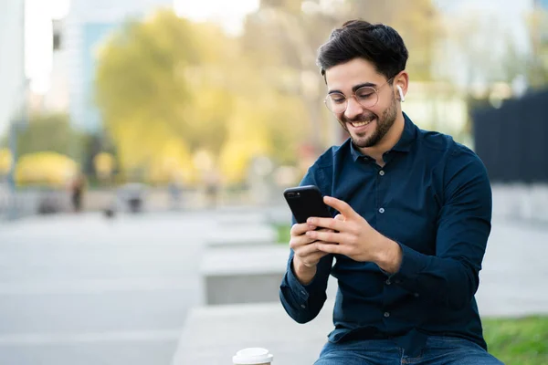 Young man using his mobile phone outdoors. — Stock Photo, Image