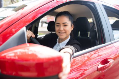 Arabadaki kadın dikiz aynasını hareket ettiriyor.