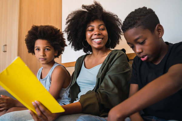 Afro mother reading a book to her children.