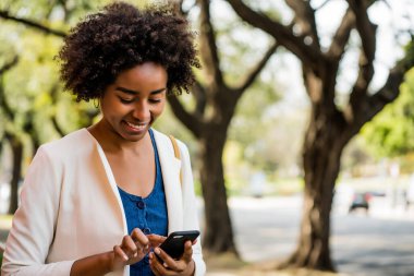 İş kadını cep telefonunu açık havada kullanıyor..