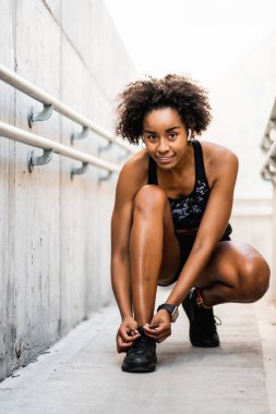 Afro atlet kadın ayakkabı bağcıklarını bağlıyor.